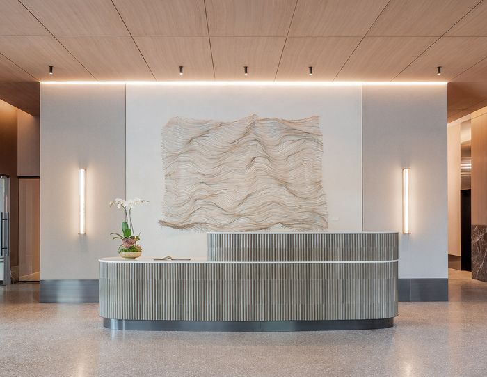 Modern lobby with elegant curved reception desk, artistic wall feature, and soft ambient lighting.