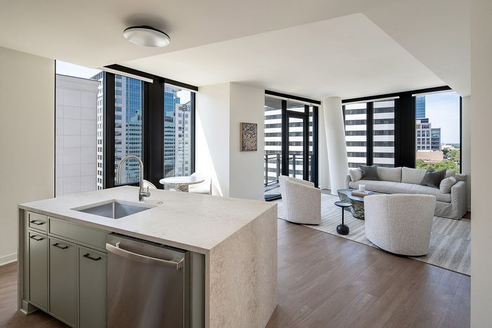 Modern high-rise apartment with sleek kitchen island, open living room, and stunning city views.
