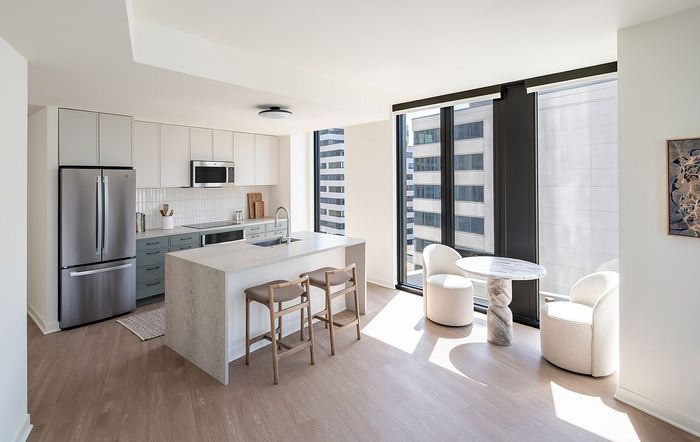 Chic modern kitchen and dining area with floor-to-ceiling windows, elegant island, and stylish seating in a luminous apartment.