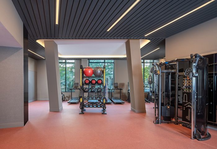 Modern gym with state-of-the-art equipment, including treadmills and weight stations, featuring sleek design and large windows for natural light.