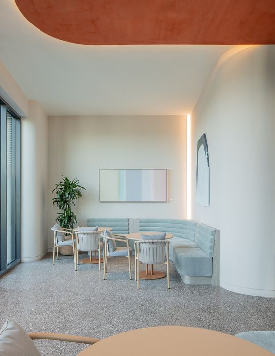 Elegant apartment seating area with cozy pastel decor, modern round tables, and abundant natural light.