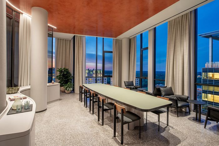 Luxurious apartment dining room with panoramic city views, modern furnishings, and elegant lighting at sunset.