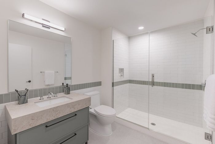 Elegant bathroom with modern walk-in shower, sleek vanity, and contemporary lighting.