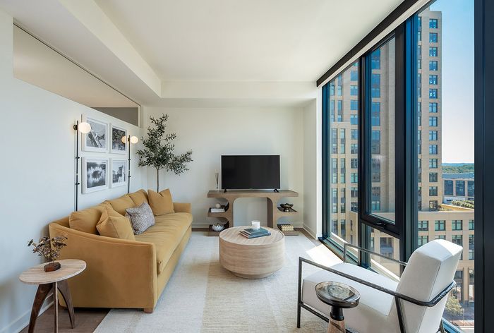 Bright, modern living room with stylish mustard sofa, large windows offering stunning city views, and tasteful decor.