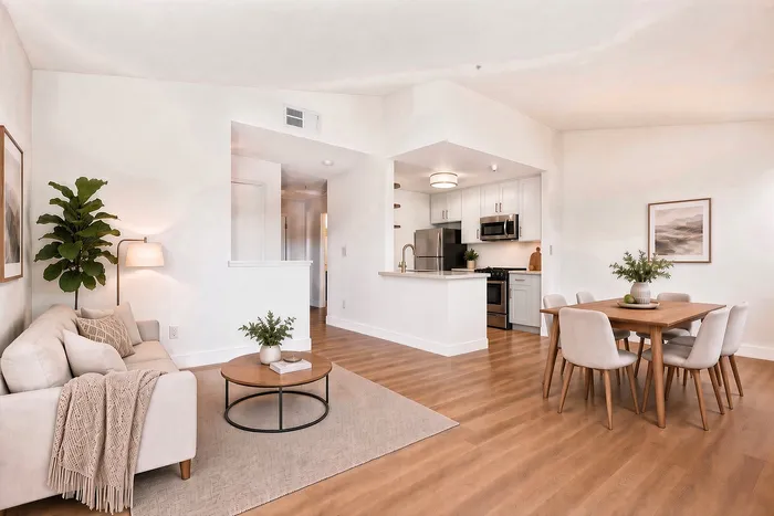 Bright and airy living space featuring sleek wood flooring, a cozy sectional, a modern open kitchen, and a stylish dining area.