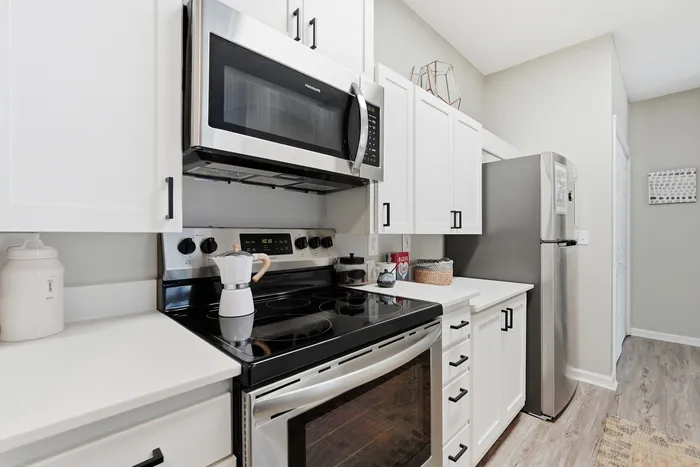 Modern kitchen with sleek stainless steel appliances, elegant white cabinetry, and stylish wood flooring, creating a perfect culinary space.