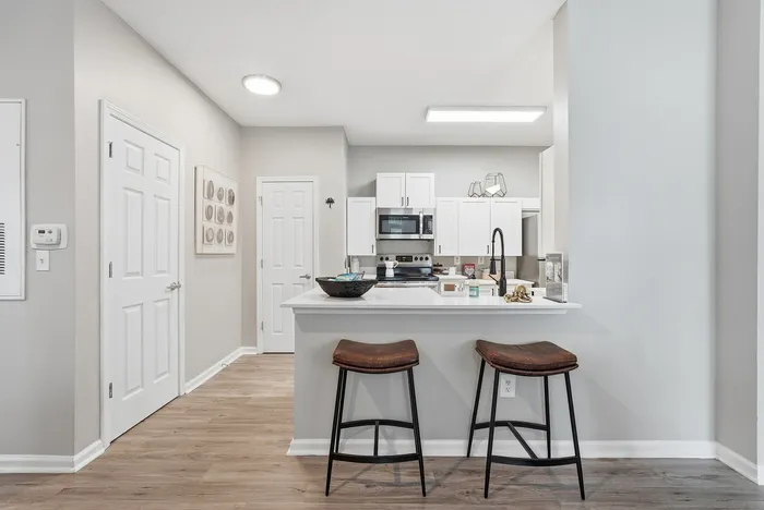 Contemporary kitchen with sleek white cabinets, modern appliances, and a cozy breakfast bar featuring stylish seating.