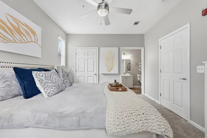 Inviting bedroom with plush bedding, stylish decor, and an ensuite bathroom showcasing modern elegance and comfort.