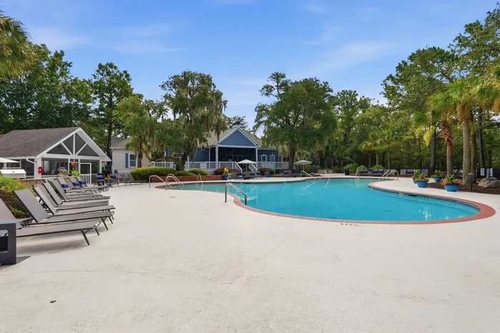 Inviting outdoor pool area with lush greenery and modern lounge chairs, perfect for relaxation and leisure.
