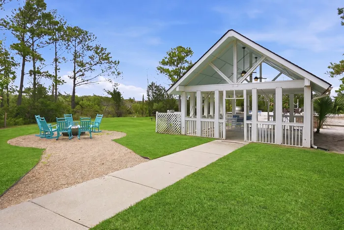 Charming outdoor pavilion surrounded by lush greenery and vibrant seating area under a clear blue sky, ideal for relaxation and gatherings.