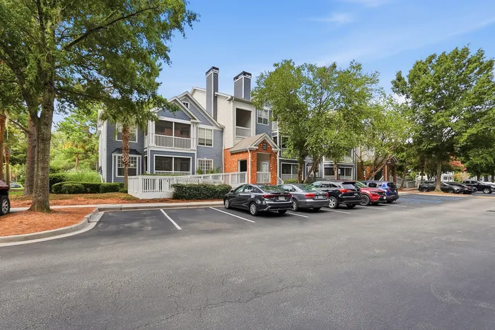 Charming apartment complex with modern architecture and ample parking, nestled amidst lush greenery.