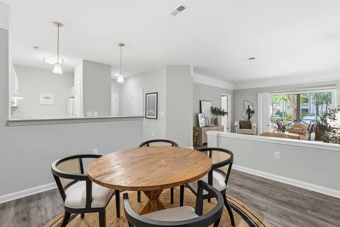 Bright and airy apartment with modern dining area, sleek kitchen, and cozy living space opening to a lush outdoor patio.