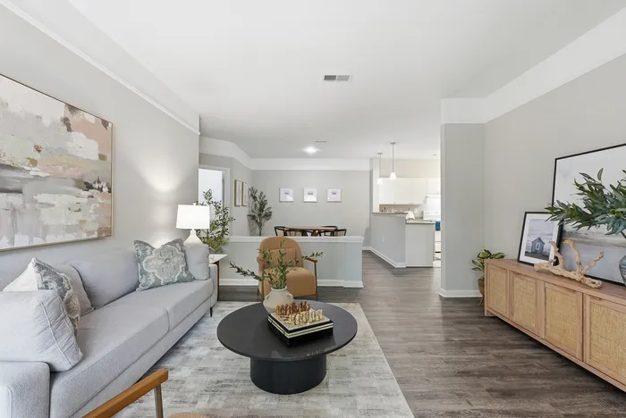 Sophisticated open-plan living area featuring a stylish gray sofa, elegant artwork, and cozy dining space leading into a modern kitchen.