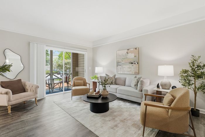 Bright and inviting living room with stylish seating, modern decor, and large sliding glass doors opening to a charming patio.
