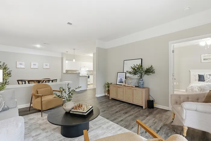 Bright and spacious living room with modern decor, open-concept design leading to a stylish kitchen, and a glimpse of a cozy bedroom, perfect for a comfortable lifestyle.