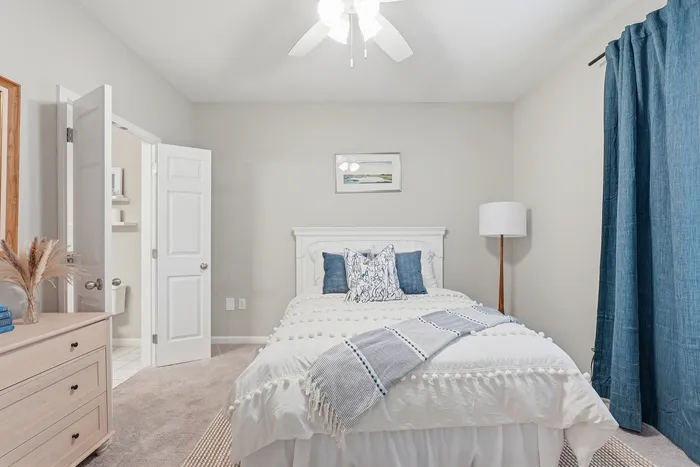Inviting bedroom with a cozy bed, elegant blue curtains, and bright natural light.