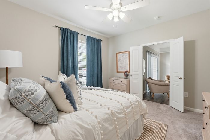Inviting bedroom with plush bedding, elegant decor, and an airy ambiance featuring natural light and modern furnishings.