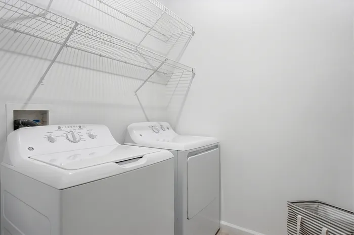 Bright laundry room featuring modern washer and dryer with spacious storage shelves, optimizing functionality and style.