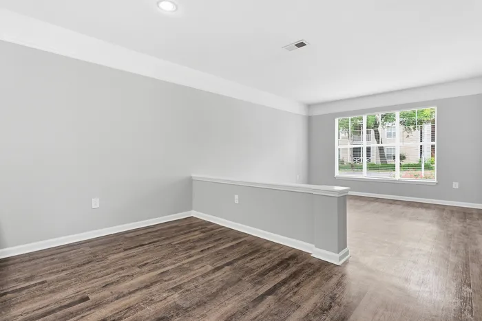 Bright, modern living space with sleek hardwood flooring, large windows, and a neutral color palette perfect for personalization.
