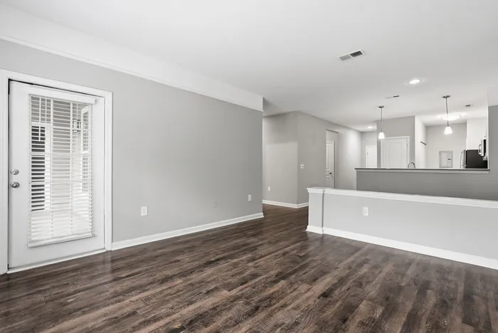 Modern open-concept living area with sleek hardwood floors, abundant natural light, and contemporary pendant lighting.