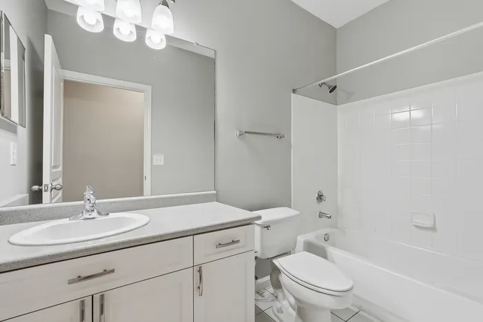 Modern bathroom showcasing sleek countertops, elegant cabinetry, and a pristine bathtub with bright lighting.