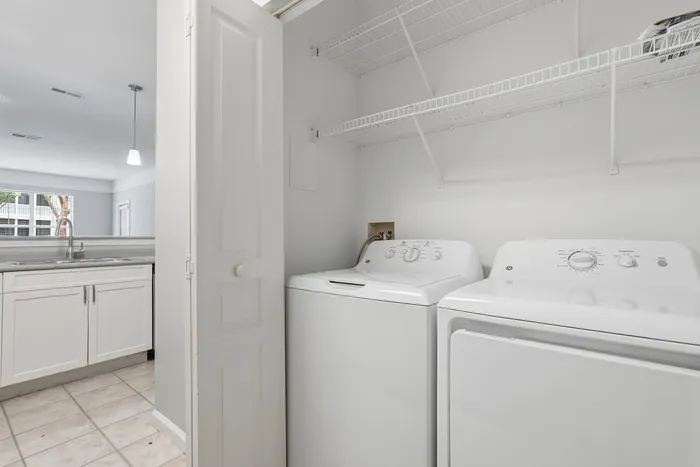 Bright and functional laundry area with white washer and dryer, adjacent to a modern kitchen with sleek cabinetry.