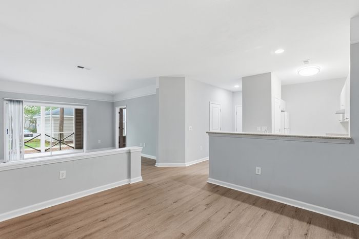 Bright open-concept living space with elegant hardwood floors and large window offering natural light.