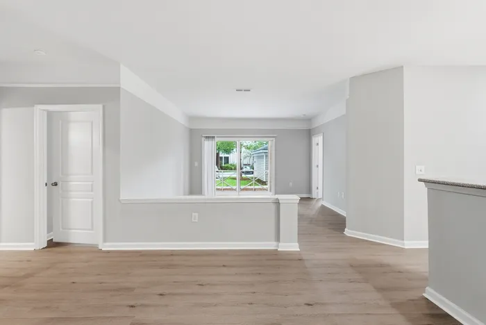 Bright and open living space with elegant hardwood floors, large windows, and a seamless flow to adjoining rooms.