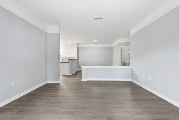 Spacious open-concept living area with elegant hardwood flooring and modern finishes, perfect for comfortable living.