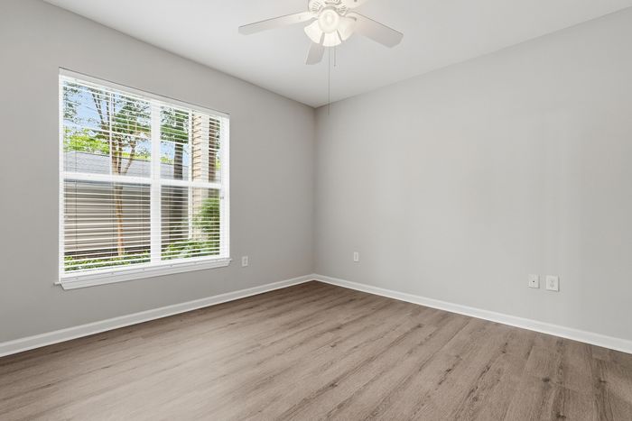 Bright empty room with large window and modern hardwood floors, perfect canvas for personalization.