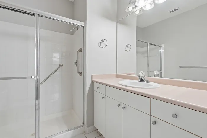 Contemporary bathroom featuring a sleek glass-enclosed shower and elegant vanity with ample storage.