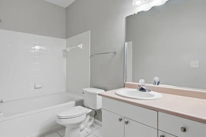 Bright and modern bathroom featuring a sleek white vanity, spacious bathtub, and elegant tile work.