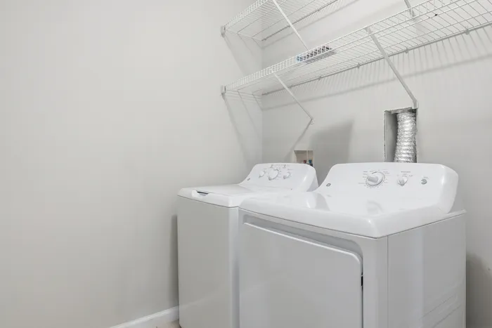 Bright laundry room with modern washer and dryer, featuring convenient wire shelving for storage solutions.