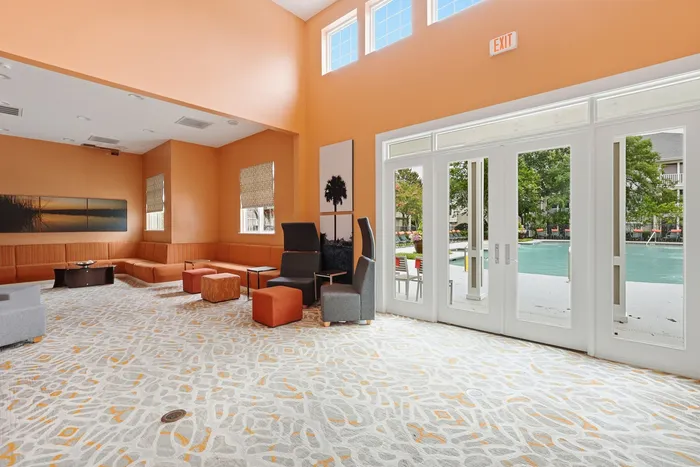 Bright and inviting communal lounge with modern seating, vibrant decor, and poolside view through large windows.