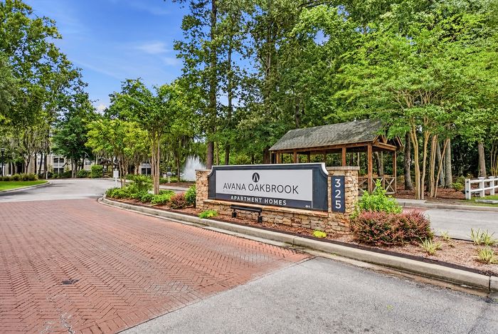 Inviting entrance to Avana Oakbrook Apartment Homes with lush greenery and a charming gazebo.