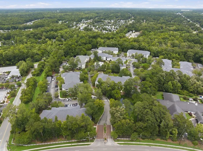 Stunning aerial view of a modern apartment community nestled within lush greenery, showcasing elegantly designed buildings and tranquil walking paths.