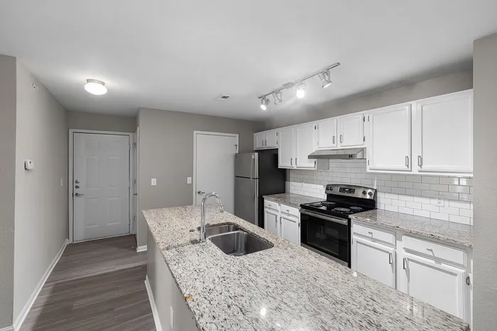 Modern kitchen with sleek granite countertops, stainless steel appliances, and elegant white cabinetry.