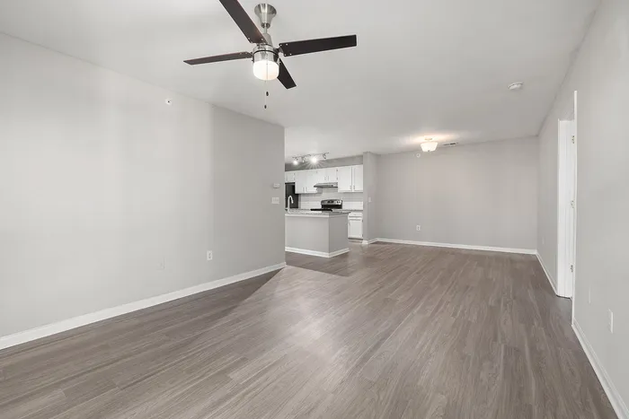 Contemporary open-concept apartment showcasing a sleek kitchen with stainless steel appliances, modern light fixtures, and elegant wood flooring.