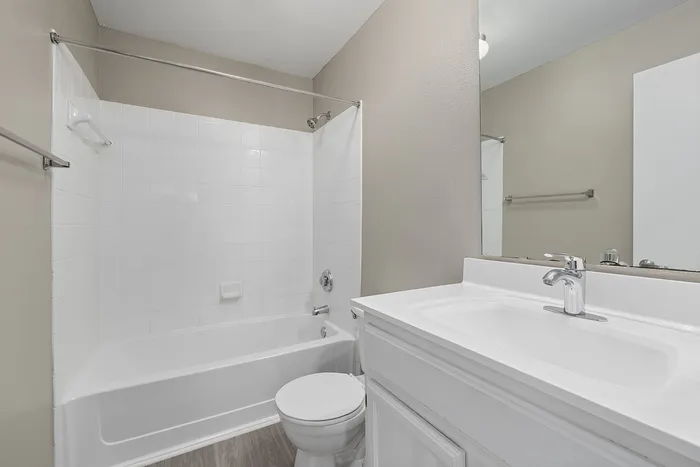 Modern bathroom with sleek white tiles, bathtub, and elegant vanity sink.