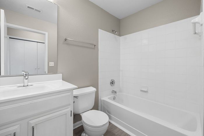 Modern bathroom with elegant white fixtures, featuring a sleek bathtub, compact vanity, and stylish mirror.