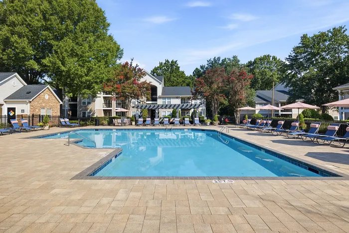 Inviting outdoor pool area surrounded by lush greenery and stylish lounge chairs, perfect for relaxation and leisure.