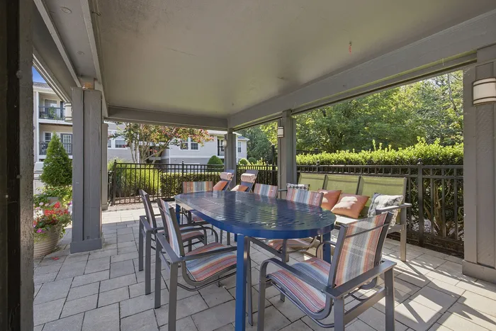 Charming covered patio with a stylish outdoor dining set, surrounded by lush greenery for a serene and inviting atmosphere.