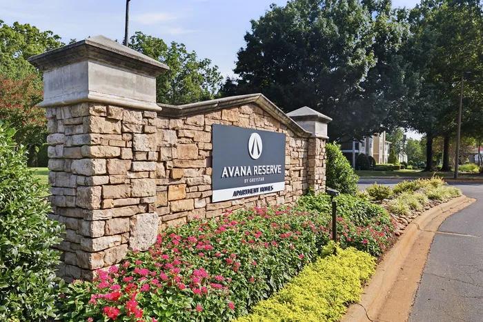 Inviting entrance to Avana Reserve Apartment Homes with elegant stonework and vibrant landscaping.