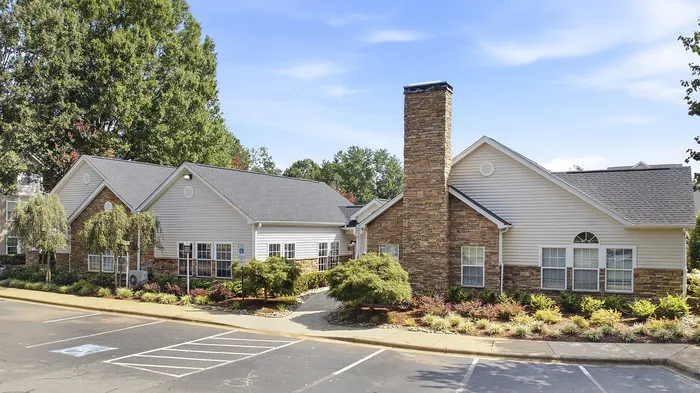 Charming suburban apartment complex with stone accents, surrounded by lush greenery and ample parking space.