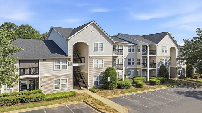 Charming three-story apartment complex with modern architecture, featuring spacious balconies and surrounded by lush greenery, offering a tranquil living environment.