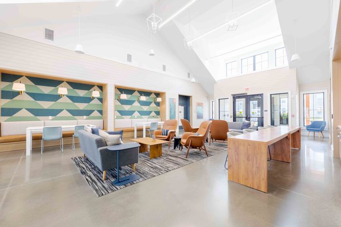 Spacious and inviting community lounge with modern furniture, vibrant geometric wall art, and abundant natural light.