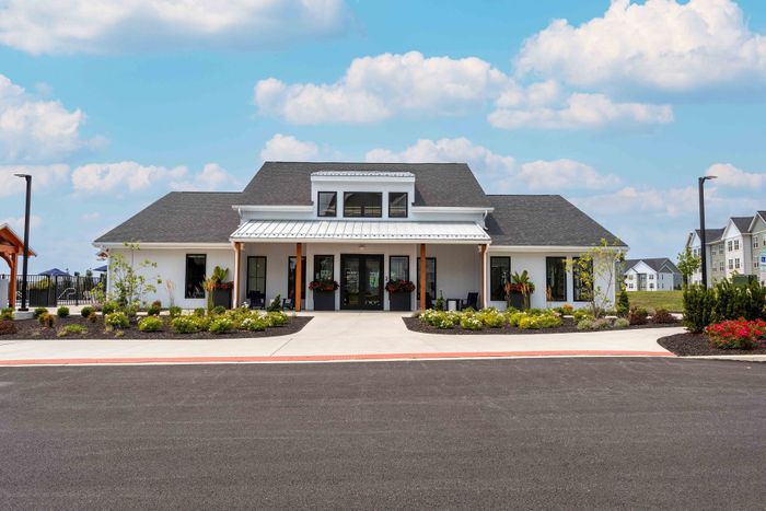 Charming residential clubhouse with beautiful landscaping and modern architecture under a vibrant blue sky.