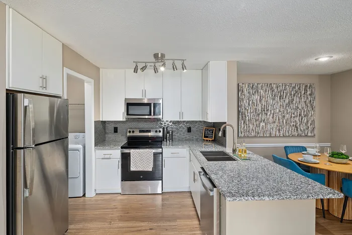 Modern kitchen with granite countertops, stainless steel appliances, and cozy dining area with elegant decor.