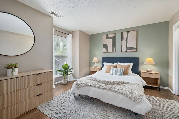 Bright and airy bedroom with modern decor, featuring a cozy bed, stylish art pieces, and natural light from large windows.