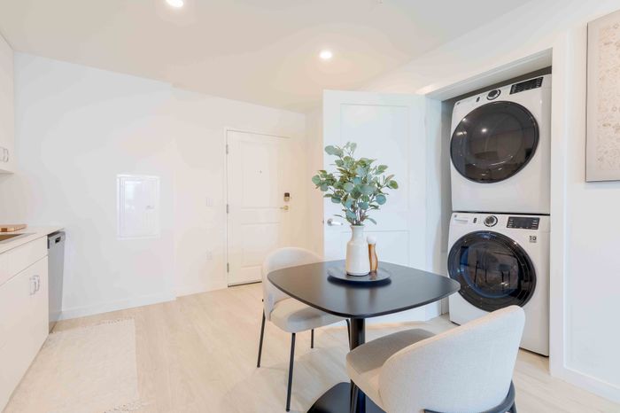 Contemporary apartment corner featuring a sleek dining table, chic chairs, and a convenient in-unit laundry setup.